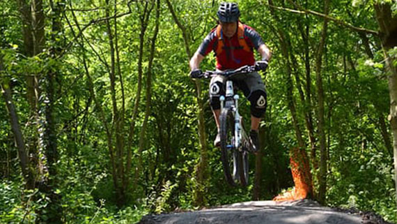 A man in riding gear riding bicycle through lush green sandwell valley country park