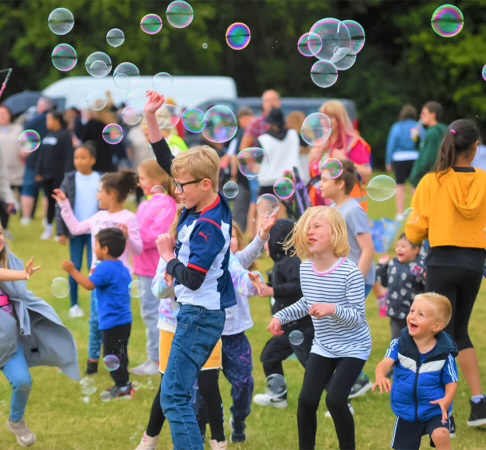 A joyful image capturing a scene of children surrounded by a cascade of colorful bubbles, their faces filled with delight and wonder. Laughter fills the air as the bubbles float and shimmer in the sunlight