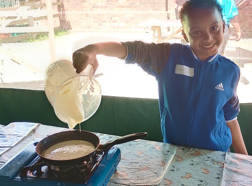 A child preparing pancakes at the farm kitchen